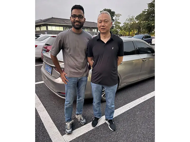 Two people standing beside a vehicle outside a facility