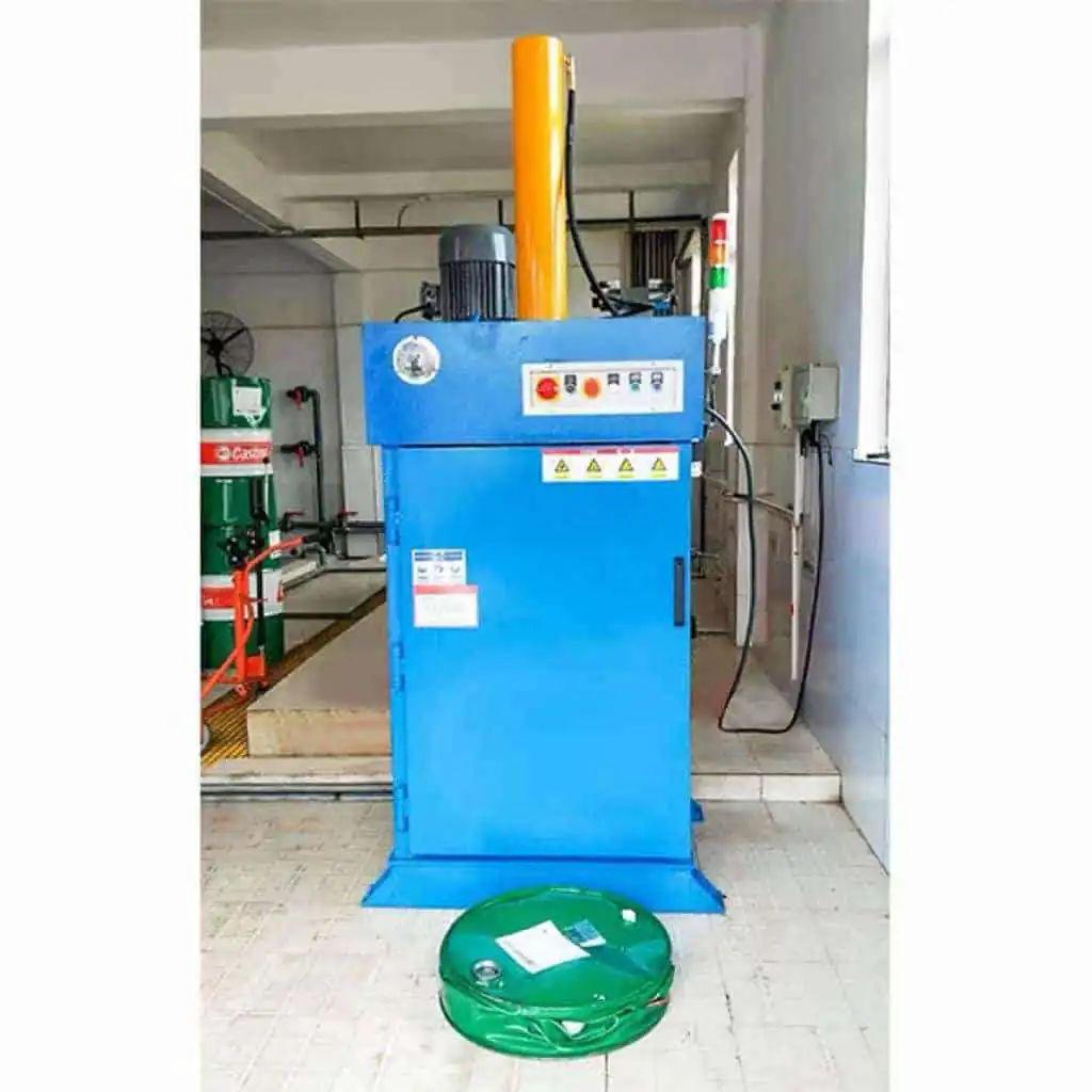 Oil drum baler in a workshop beside a compressed drum